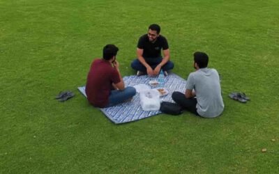 Three friends having a picnic on a green lawn in Sheikha Fatima Park